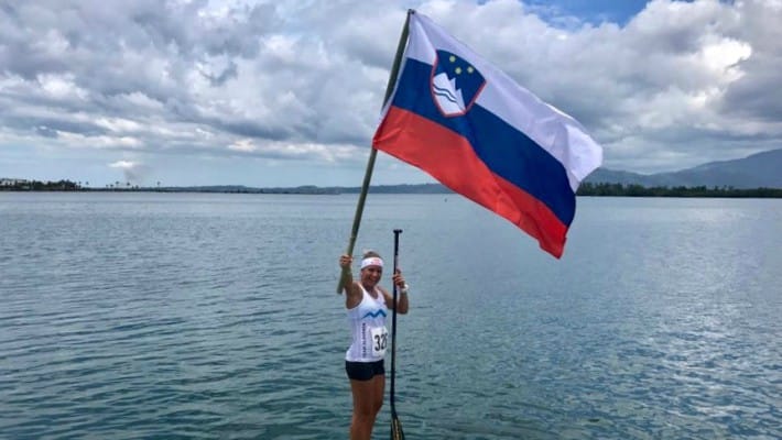 Slovenian SUP star Manca Notar waves the Slovenian flag during a flatwater SUP training session in her homeland