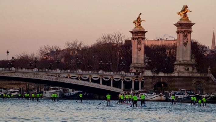 Paddlers race past the ornate Alexandre III bridge in Paris