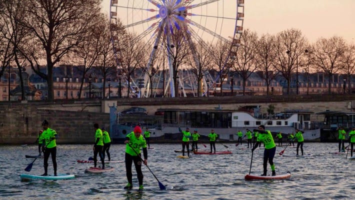 Participating paddlers pass by the quays by the Tuileries gardens in central Paris at the 2016 Nautic SUP Paris Crossing