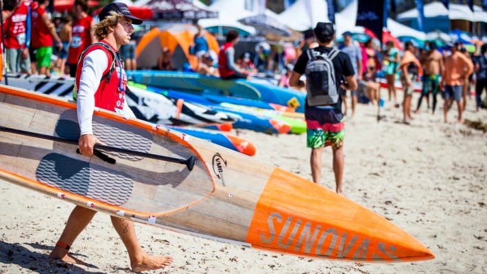James Casey walks with his Sunova board to the shore, ready to take off at another Australia-based SUP event