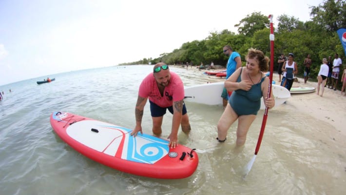 Philippe Momparler assists a new paddler at the inauguration of his O Lagon paddling and watersports equipment service in Saint-Martin